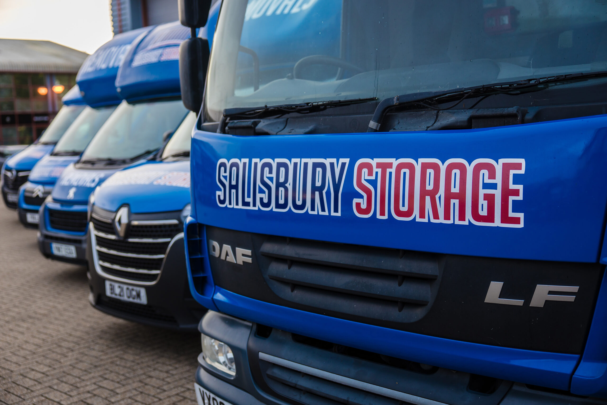 Close up of salisbury removals blue vans and lorries parked in front of a warehouse.