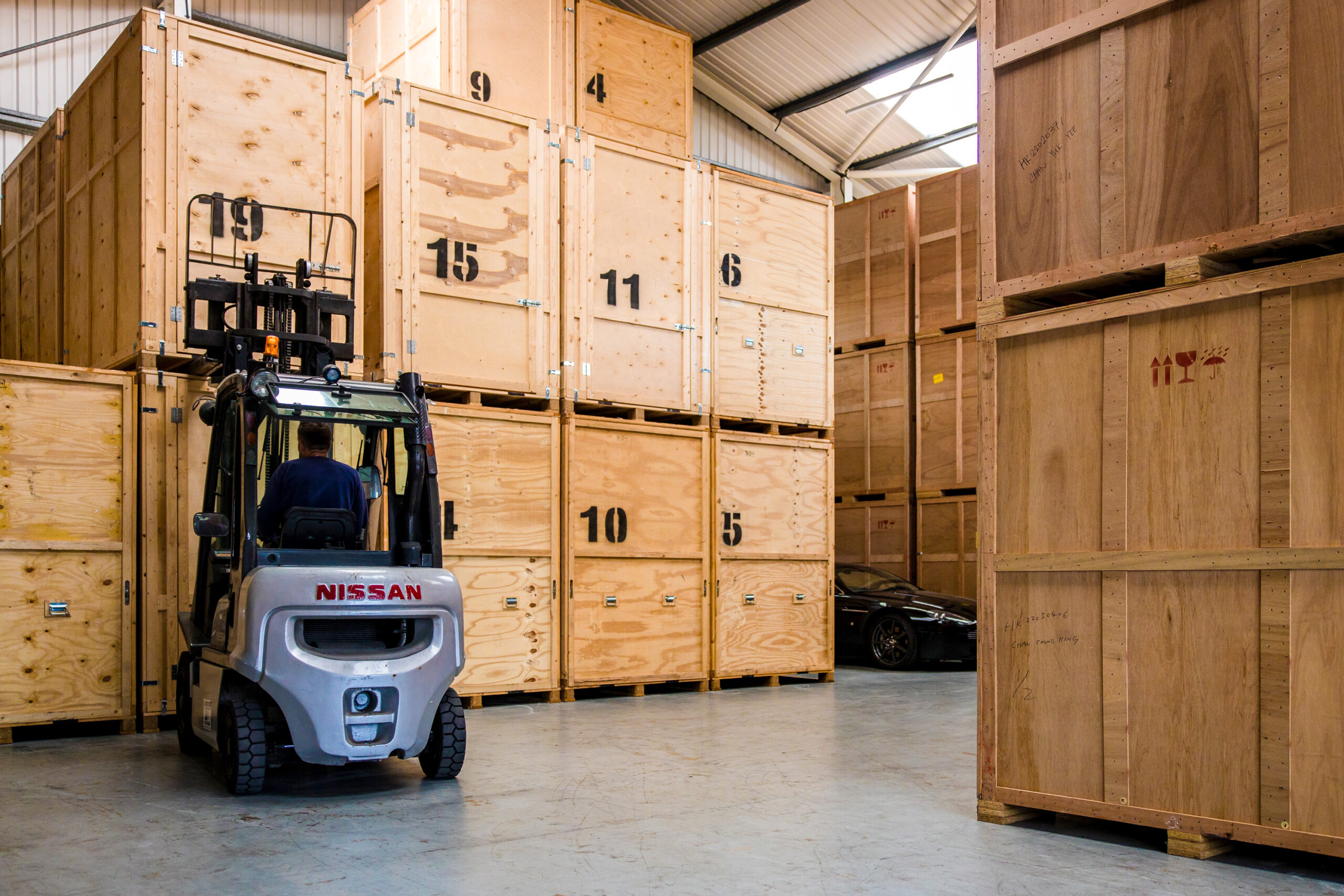 A forklift truck manoeuvring in a warehouse, transporting large wooden storage boxes efficiently.