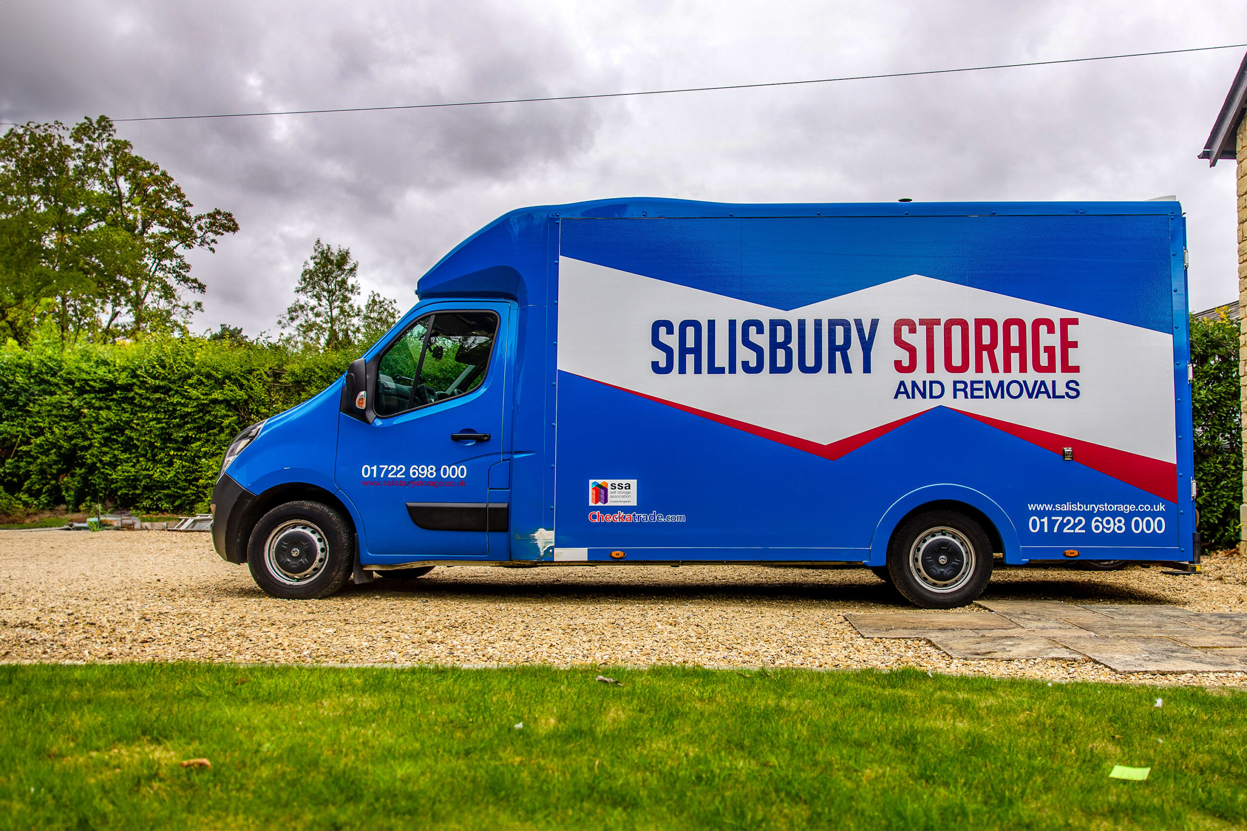 A blue salisbury storage and removals van parked on a stoney drive.