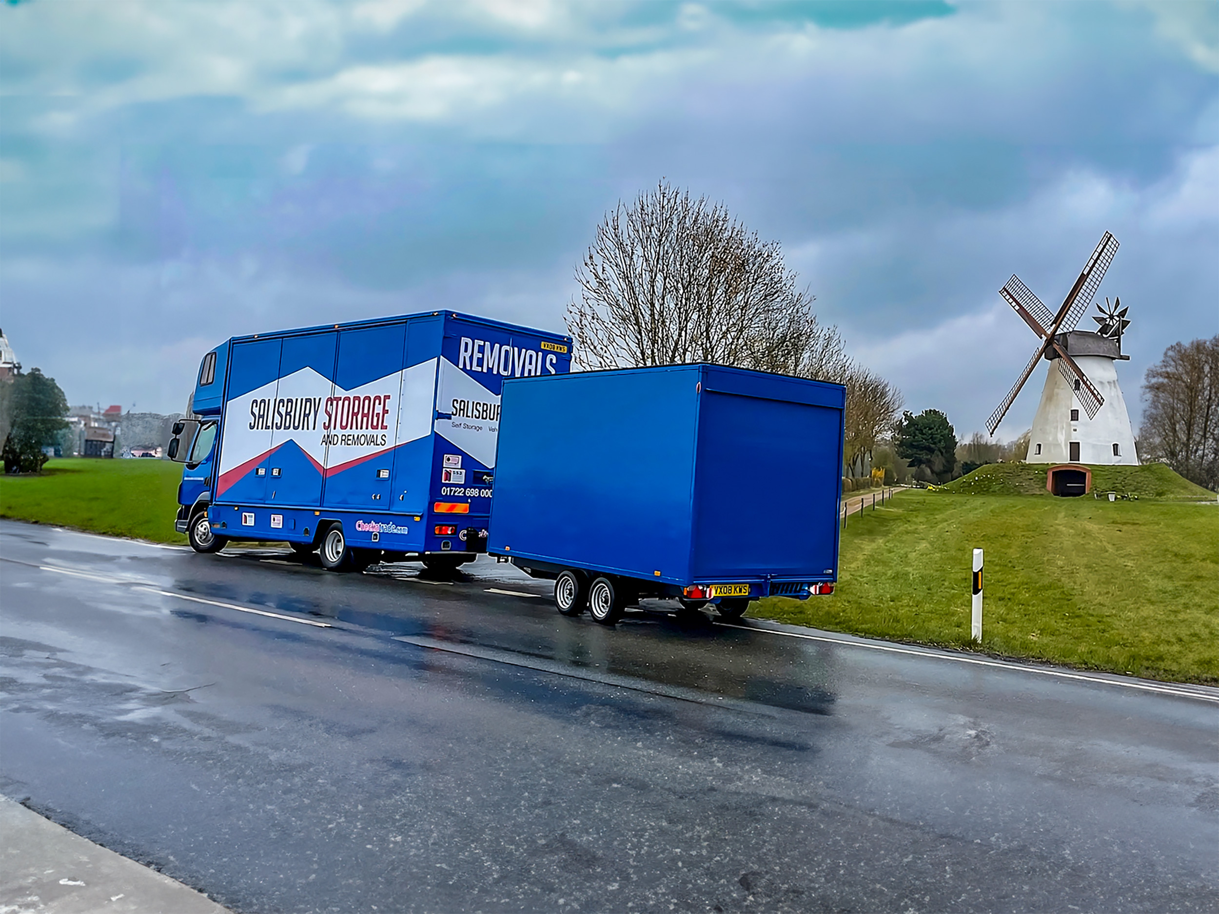 A blue salisbury storage and removals lorry pulling a blue trailer journeying through a european country.
