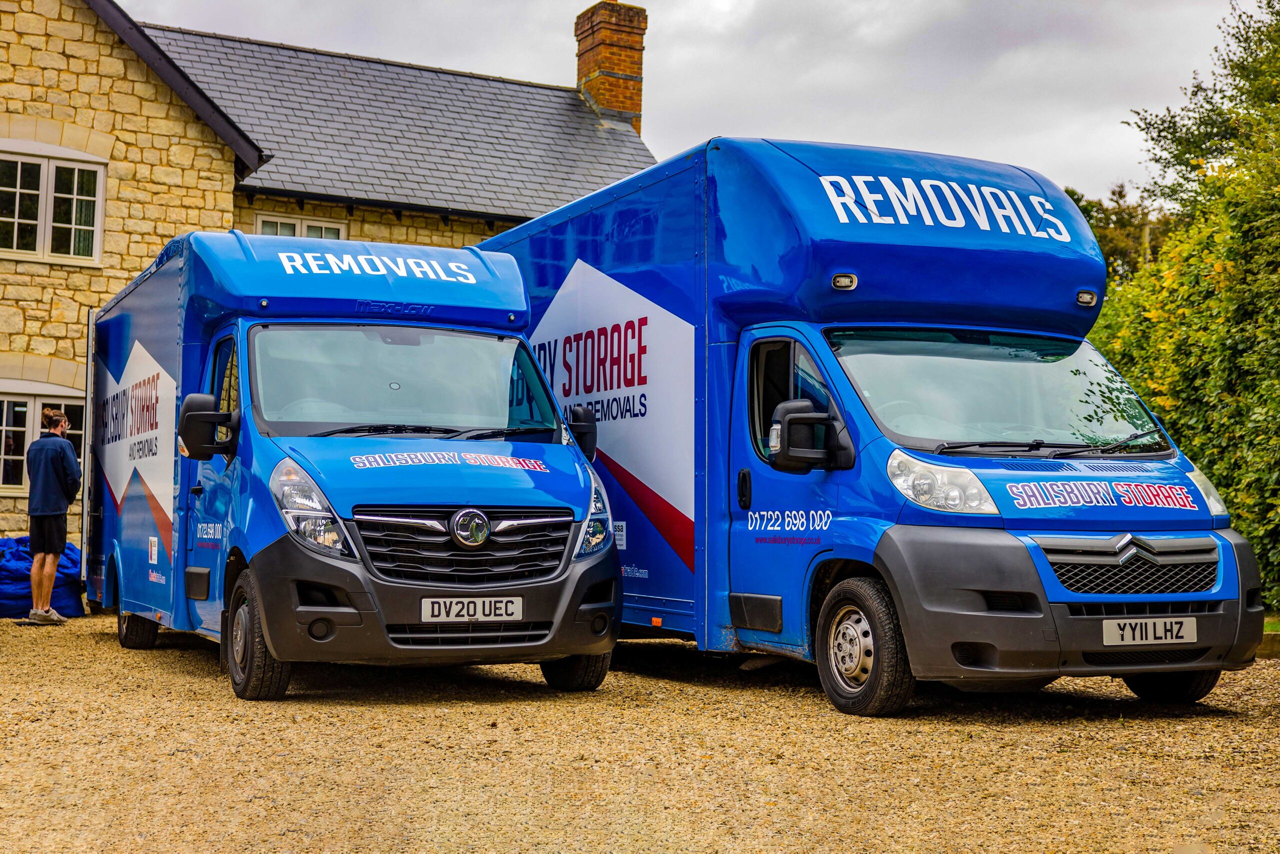 Two blue salisbury storage and removals vans parked in front of a house, ready to transport belongings.