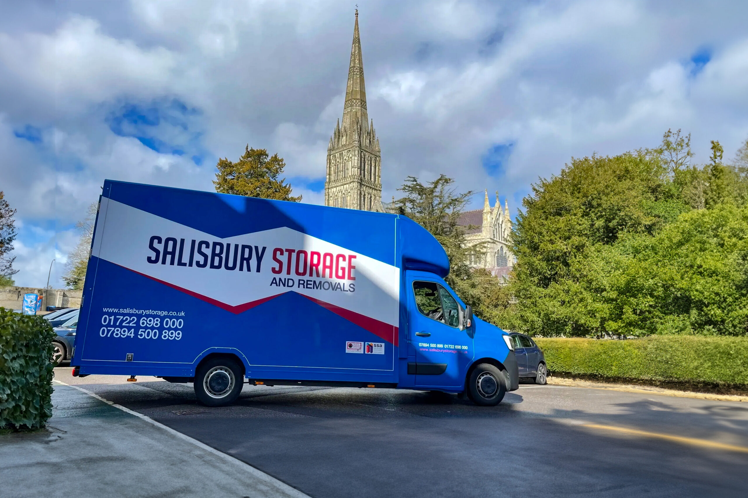 Salisbury and removals and storage van in a car park with salisbury cathedral in the background.