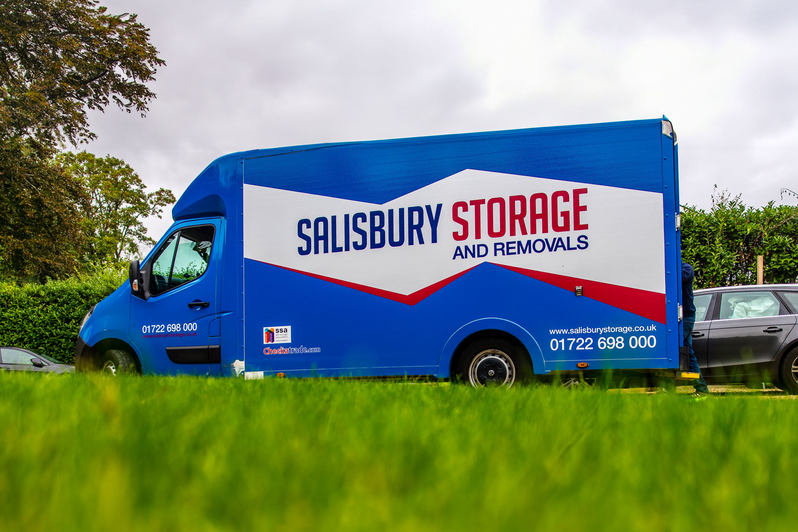 Salisbury storage and removals van parked on a drive with close up of blurry grass at the bottom.